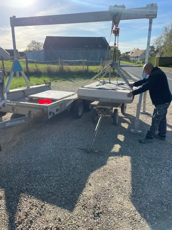 Transport et livraison de pièces de marbrerie funéraire avec un équipement de levage.