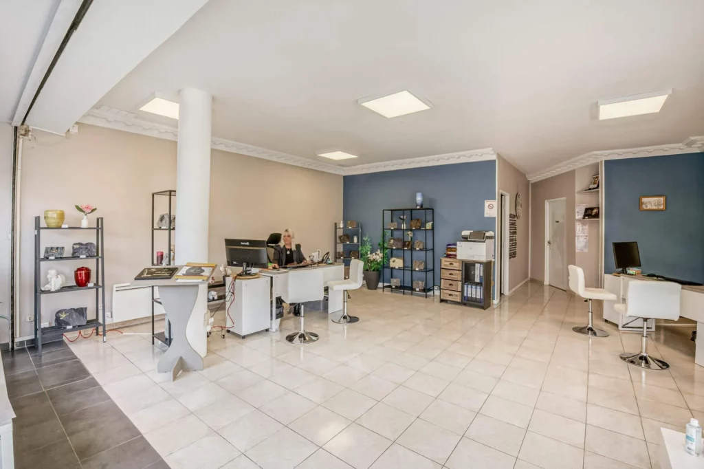 Bureau d'accueil d'une agence de pompes funèbres avec urnes et plaques de marbrerie.