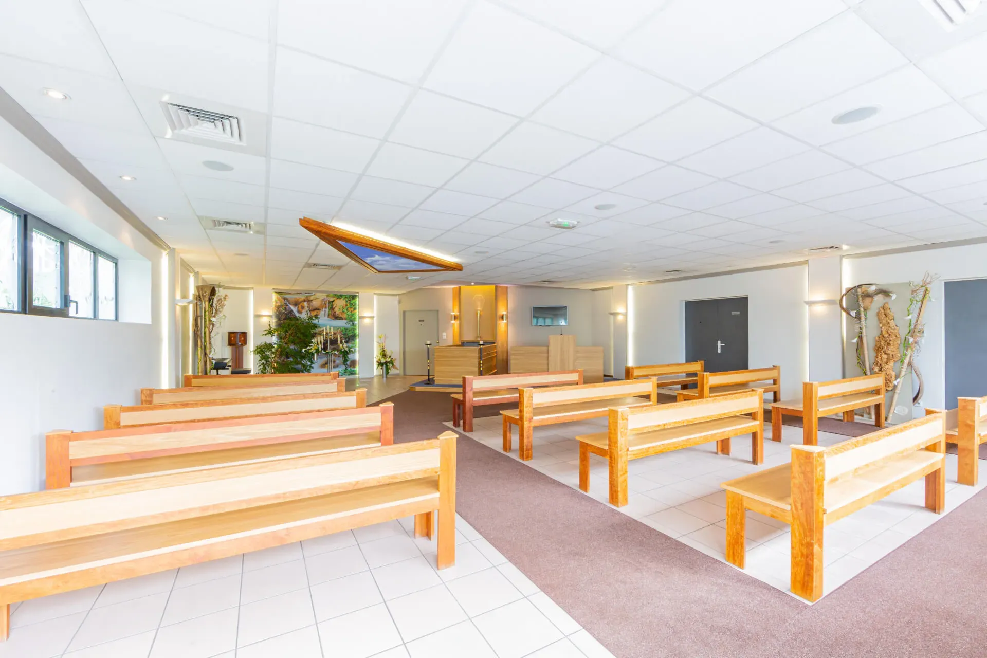 Salle de cérémonie civile funéraire moderne avec bancs en bois clair.