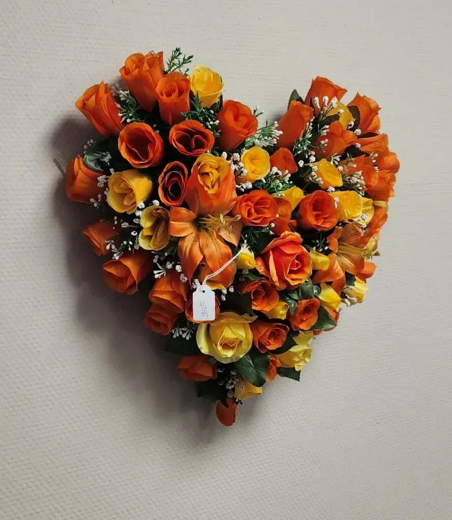 Cœur de fleurs artificielles funéraires orange et jaunes.