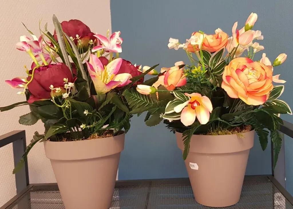Deux pots de fleurs artificielles funéraires colorées.