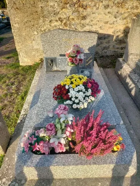Tombe fleurie de manière colorée pour la Toussaint dans un cimetière ensoleillé.
