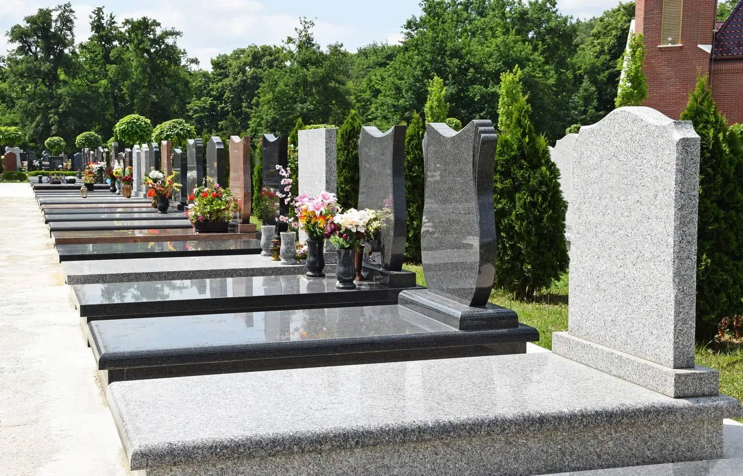 Alignement de monuments funéraires en granit dans une allée de cimetière.