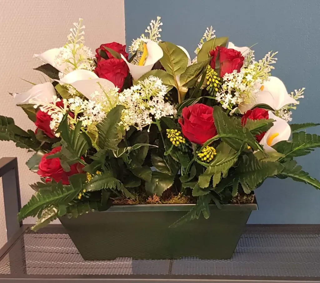 Jardinière funéraire de fleurs artificielles rouges et blanches.